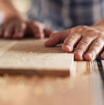 Hands of a real woodworker sawing a piec